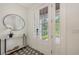 The foyer has a gray tile floor, a round mirror and decorative white flowers at 2590 Floyd St, Sarasota, FL 34239