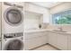 A modern laundry room featuring a stacked washer and dryer and plenty of cabinet storage and a window at 2590 Floyd St, Sarasota, FL 34239