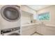 A modern laundry room featuring a stacked washer and dryer and plenty of cabinet storage and a window at 2590 Floyd St, Sarasota, FL 34239