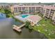 Aerial view of a lakeside condo with a pool, dock with canopy, clubhouse and lush landscaping at 3635 Lake Bayshore Dr # J-410, Bradenton, FL 34205
