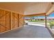 View of the covered carport, featuring a painted floor and access to wooden storage at 3850 Catalina Dr, Bradenton, FL 34210