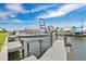 View of the dock with a boat lift and a boat with waterfront homes and blue sky in the background at 3850 Catalina Dr, Bradenton, FL 34210