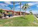 Charming waterfront home featuring lush lawn, patio area with seating, and tall palm trees against a blue sky at 3850 Catalina Dr, Bradenton, FL 34210