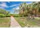 Beautifully landscaped community space with manicured lawn, walking path and benches and palm trees at 3850 Catalina Dr, Bradenton, FL 34210