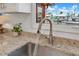 Close-up of a stainless steel sink with a modern faucet and granite countertops, with a window view at 3850 Catalina Dr, Bradenton, FL 34210
