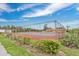 Outdoor tennis court with a red clay surface and surrounding greenery under a bright blue sky at 3850 Catalina Dr, Bradenton, FL 34210