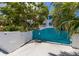 Exterior shot showcasing the driveway, unique blue gate, and lush landscaping at 401 N Bay Blvd, Anna Maria, FL 34216