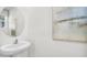Elegant half bathroom featuring a pedestal sink, round mirror and modern art, enhancing its appeal at 4104 Gold Dust Ln, Sarasota, FL 34243