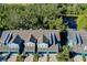 Aerial view showcasing the blue townhomes, dark roofs, and surrounding trees and pond at 4532 Chinkapin Dr, Sarasota, FL 34232