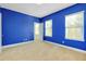 Bedroom featuring neutral carpet, base molding, three windows, and vibrant blue walls at 4532 Chinkapin Dr, Sarasota, FL 34232