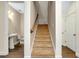 Bright hallway featuring a carpeted staircase with wooden railing and adjacent powder room with wood-look floors at 4532 Chinkapin Dr, Sarasota, FL 34232