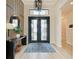 Elegant foyer with modern chandelier, patterned accent wall, and glass paneled double doors at 4915 Kiva Cir, Bradenton, FL 34211