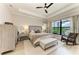 Bright main bedroom featuring a tray ceiling, ceiling fan, light wood floors, and a large window with a view at 4915 Kiva Cir, Bradenton, FL 34211