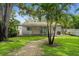 Well-maintained backyard featuring a covered patio, green lawn, and lush tropical landscaping at 5702 Tangerine S Ave, Gulfport, FL 33707