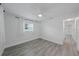 Bright bedroom features sleek gray flooring, ceiling fan, and natural light from a window with white curtains at 5702 Tangerine S Ave, Gulfport, FL 33707