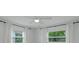 Bright bedroom with two windows, white walls, gray flooring, and a ceiling fan with light at 5702 Tangerine S Ave, Gulfport, FL 33707