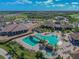 Aerial view of the community pool with lounge chairs, cabanas, lush landscaping, and clubhouse in the distance at 5916 Wake Forest Run # 101, Bradenton, FL 34211