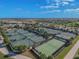 Aerial view of the community tennis courts surrounded by neighborhood homes, green spaces, and tennis players at 5916 Wake Forest Run # 101, Bradenton, FL 34211