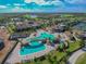 Aerial view of community pool with rock features, lounge seating, and lush landscaping, with the clubhouse nearby at 5916 Wake Forest Run # 101, Bradenton, FL 34211