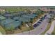 Aerial view showcasing the tennis courts with players in a scenic community with lush landscaping and parking at 5916 Wake Forest Run # 101, Bradenton, FL 34211