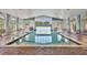 Inviting indoor pool with clear water, brick trim, and plenty of natural light from the large windows at 6312 41St E Ct, Sarasota, FL 34243