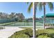 Outdoor tennis court with green fence in a sunny location featuring a view of a pond at 6312 41St E Ct, Sarasota, FL 34243