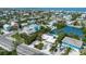 Aerial view of colorful neighborhood homes, lush foliage, a canal, and Gulf waters beyond at 6806 Palm Dr, Holmes Beach, FL 34217