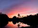 Sunset over water featuring pink and orange skies with silhouetted trees and palm trees at 6806 Palm Dr, Holmes Beach, FL 34217