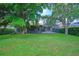 Manicured backyard featuring a green lawn, mature trees, and a screened-in patio at 695 Rivendell Blvd, Osprey, FL 34229