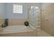 Bright bathroom featuring soaking tub with jets and glass block window to shower at 695 Rivendell Blvd, Osprey, FL 34229