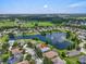 Stunning aerial view of the home nestled by a peaceful lake with a fountain and well-maintained lawns at 7026 43Rd E Ave, Palmetto, FL 34221