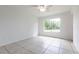 Open bedroom with neutral walls, tile floors, ceiling fan, and a large window overlooking the outdoors at 7164 Gama Ct, North Port, FL 34287