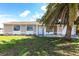Charming single-story home with an attached two-car garage framed by a lush green lawn and swaying palm tree at 7164 Gama Ct, North Port, FL 34287