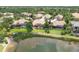 A stunning aerial view showcases a community pool and lake with verdant lawns and tropical landscaping at 7605 Haddington Cv, Lakewood Ranch, FL 34202
