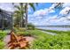 Relaxing backyard with brick patio, seating, and scenic lake views with mature palm trees at 7605 Haddington Cv, Lakewood Ranch, FL 34202