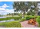 Inviting backyard features a brick patio with chairs, a serene lake view, and lush landscaping at 7605 Haddington Cv, Lakewood Ranch, FL 34202