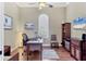 Bright office with hardwood floors, a large desk, a ceiling fan, and a built-in bookcase at 7605 Haddington Cv, Lakewood Ranch, FL 34202