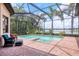 Screened-in pool area with brick patio, lush landscaping and a view of the lake at 7605 Haddington Cv, Lakewood Ranch, FL 34202