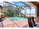 Screened-in pool area with brick patio, lush landscaping and a view of the lake at 7605 Haddington Cv, Lakewood Ranch, FL 34202