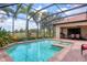 Outdoor swimming pool with spa, brick patio, screened enclosure, built-in grill, and lush landscaping at 7605 Haddington Cv, Lakewood Ranch, FL 34202