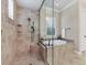 A main bathroom is equipped with a glass-enclosed shower and adjacent tub, both featuring tile and stone details at 7605 Haddington Cv, Lakewood Ranch, FL 34202