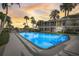 Community pool at dusk featuring palm trees, lounge chairs and a well maintained condo building in the background at 999 Inlet Cir # 103, Venice, FL 34285