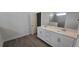 Bathroom featuring dual sinks, white cabinets, and a tiled shower at 15115 Oxford Grey Dr, Bradenton, FL 34211