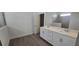 Bathroom featuring dual sinks, white cabinets, and a tiled shower at 15115 Oxford Grey Dr, Bradenton, FL 34211
