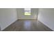Well lit empty bedroom with wood-look tiling and large window overlooking the lawn at 15115 Oxford Grey Dr, Bradenton, FL 34211