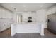 Well-lit kitchen featuring white cabinets, a large island, quartz countertops, and a stainless fridge at 15115 Oxford Grey Dr, Bradenton, FL 34211