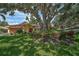Charming single-story home featuring a terracotta tile roof, beautiful landscaping, and a large shade tree at 1674 Cottonwood Trl, Sarasota, FL 34232