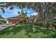 Charming single-story home featuring a terracotta tile roof, beautiful landscaping, and a large shade tree at 1674 Cottonwood Trl, Sarasota, FL 34232