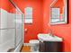 Bathroom with bright red walls, a shower with glass doors, and a modern sink and toilet at 1911 26Th W St, Bradenton, FL 34205