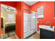 A bathroom featuring bright red walls, a shower with glass doors and a modern sink at 1911 26Th W St, Bradenton, FL 34205